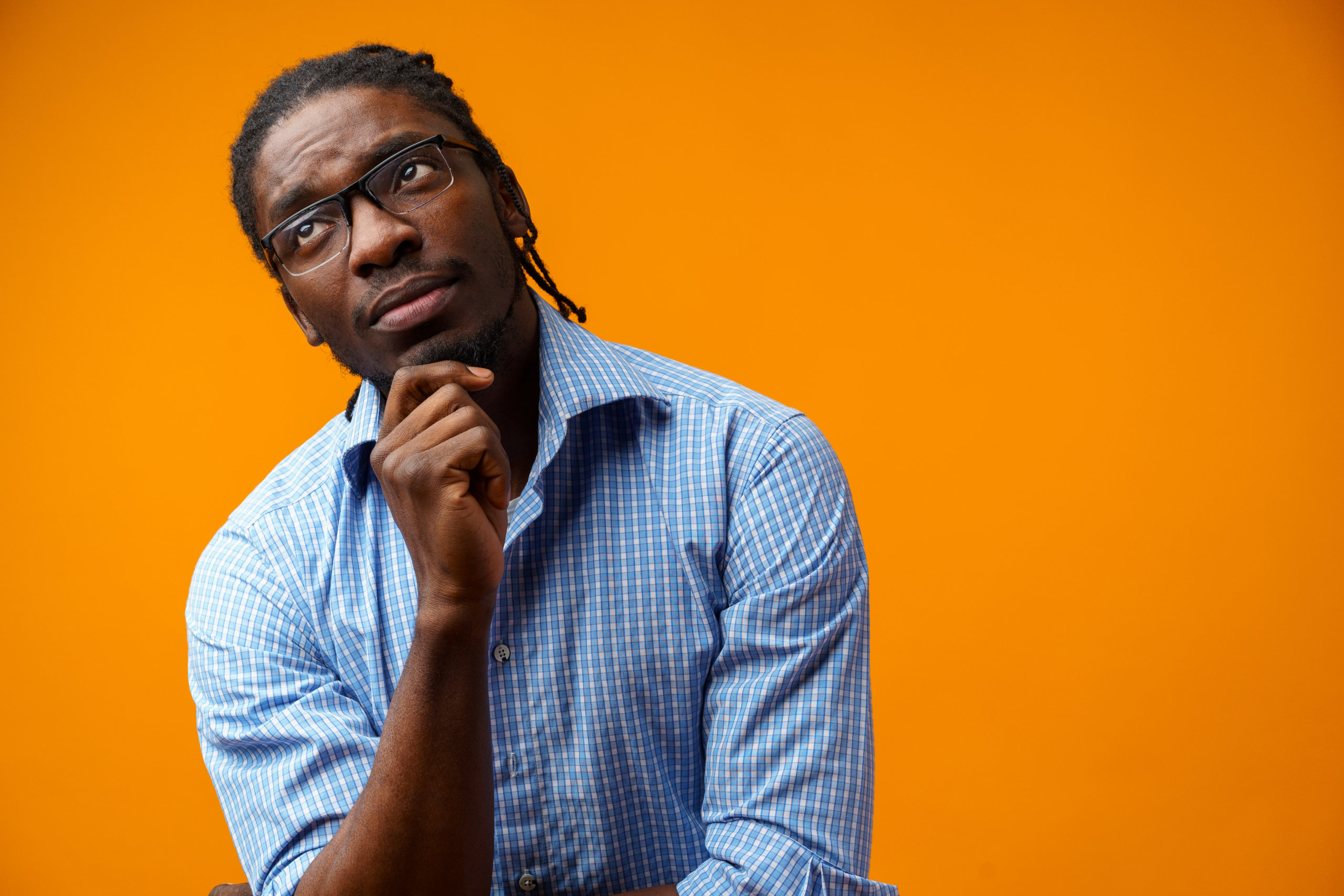 Pensive afro man portrait on orange background